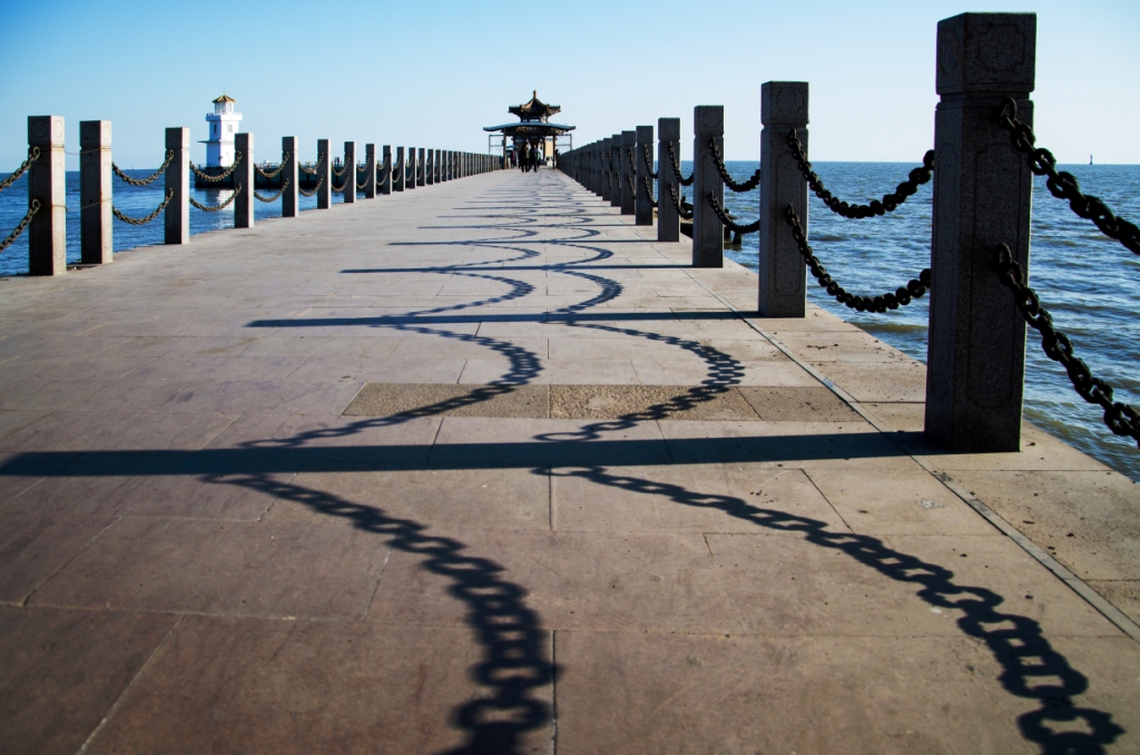 海边的下午,阳光斜照与风波堤的护栏上,像波浪的影子蜿蜒向海.
