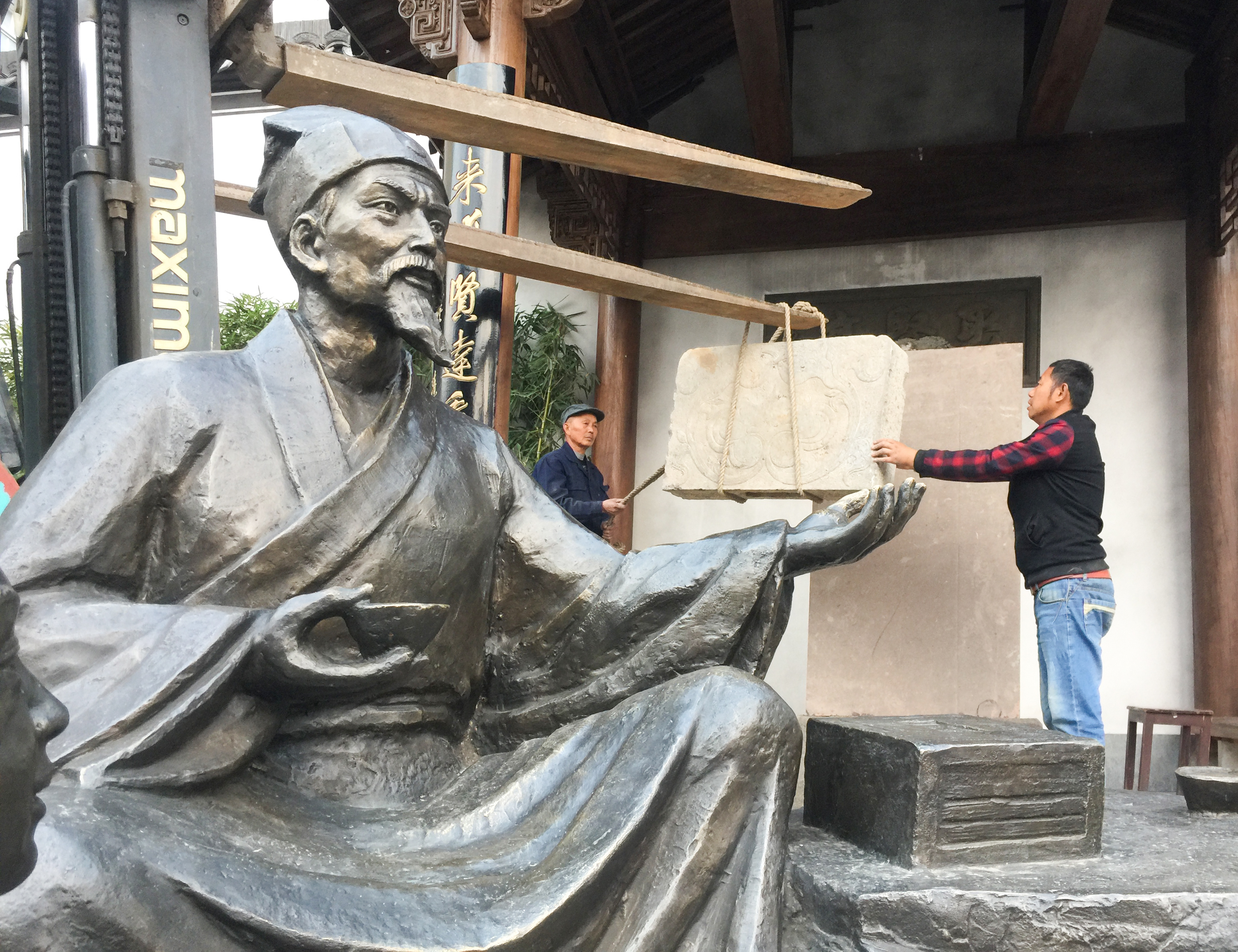 寿昌古镇工人们正在雕像后吊装碑,古人为辛苦的工作的子孙伸出强壮