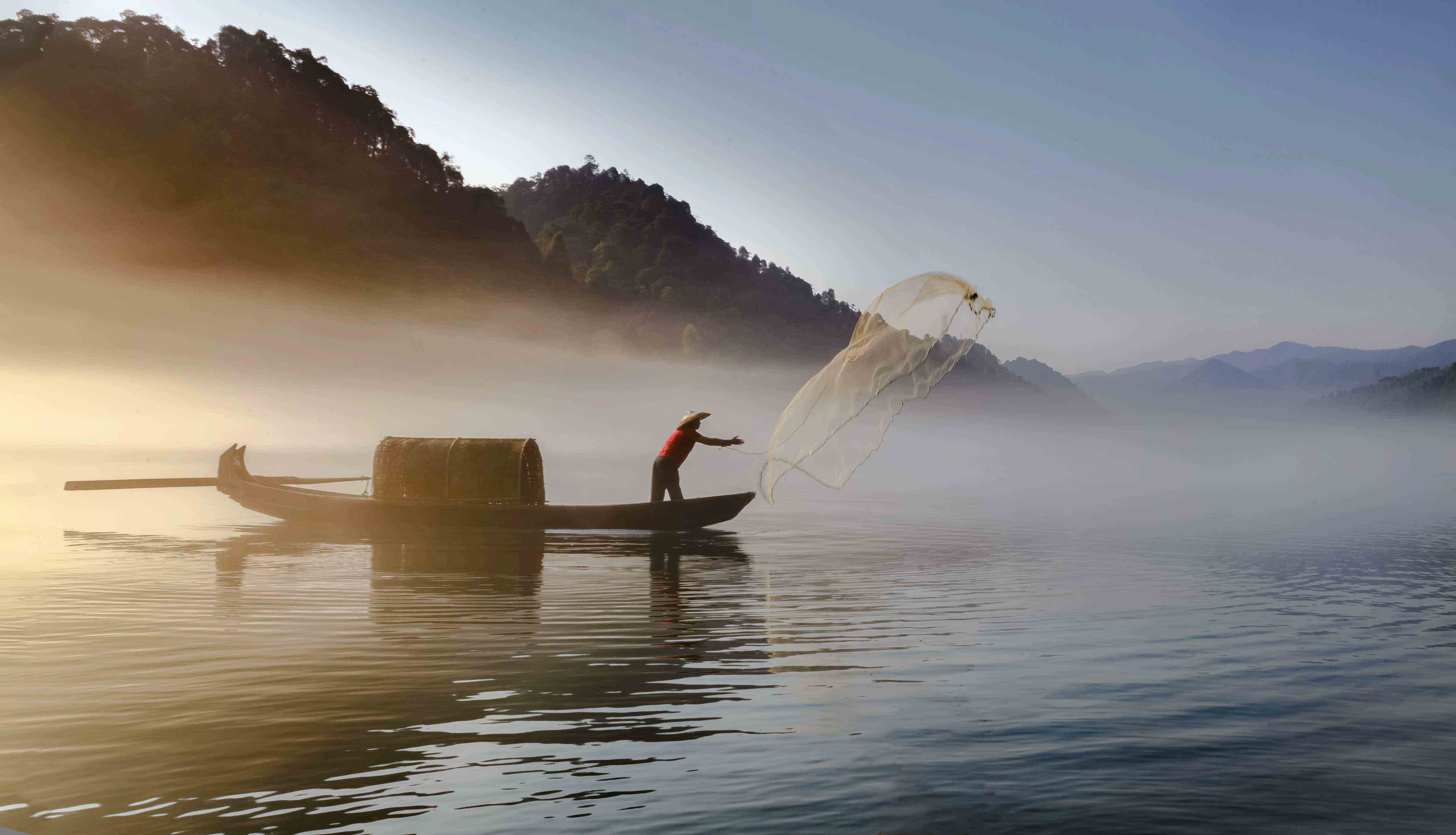 湖南省资兴市小东江渔夫在晨雾中撒网.