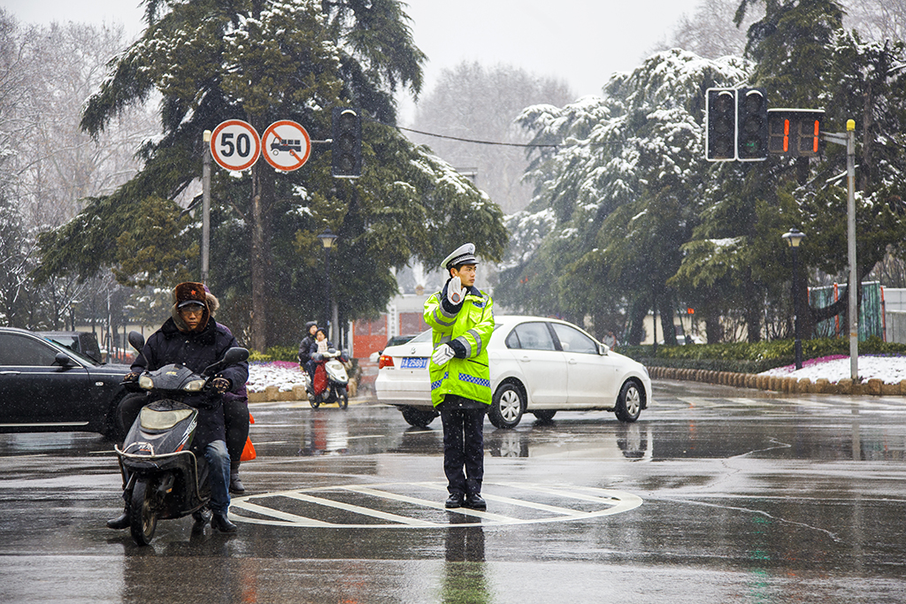 2015年1月29日,南京北京东路,公安交警冒雪在指挥着交通,保安全.