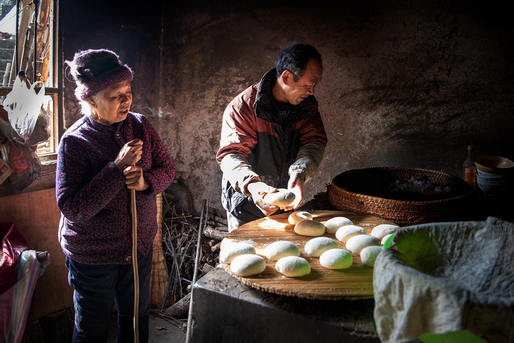 年2月1日拍摄于河南省南召县城郊乡大庄村,一贫困户母亲教儿子蒸馒头