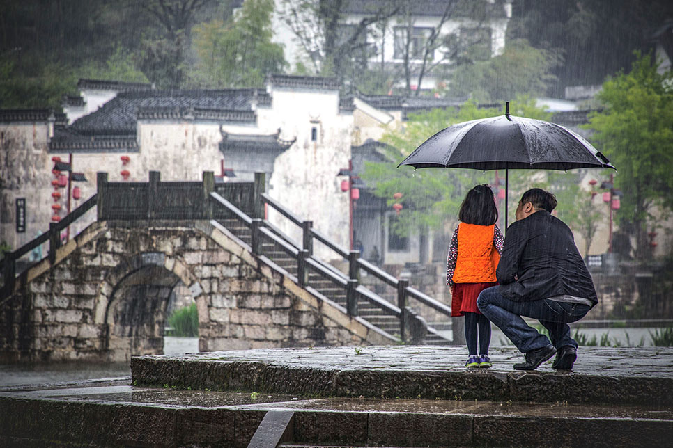 画面中,一位父亲为女儿打着伞,在古香古色的徽派建筑中,散发着温情