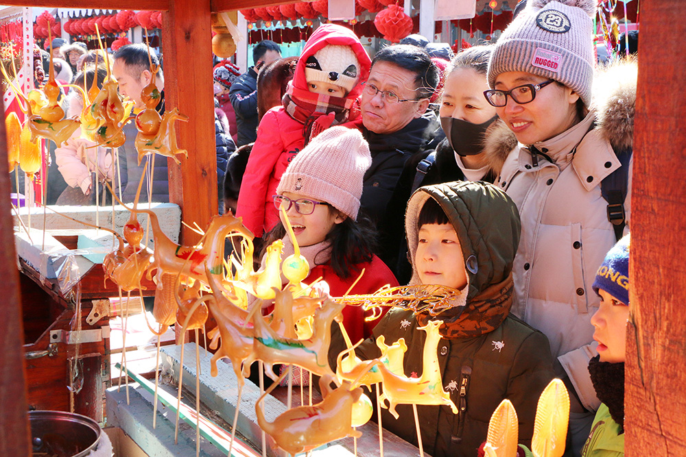 2019年2月9日 辽宁沈阳新春祈福皇寺庙会,一传统吹糖人儿展台前,孩子