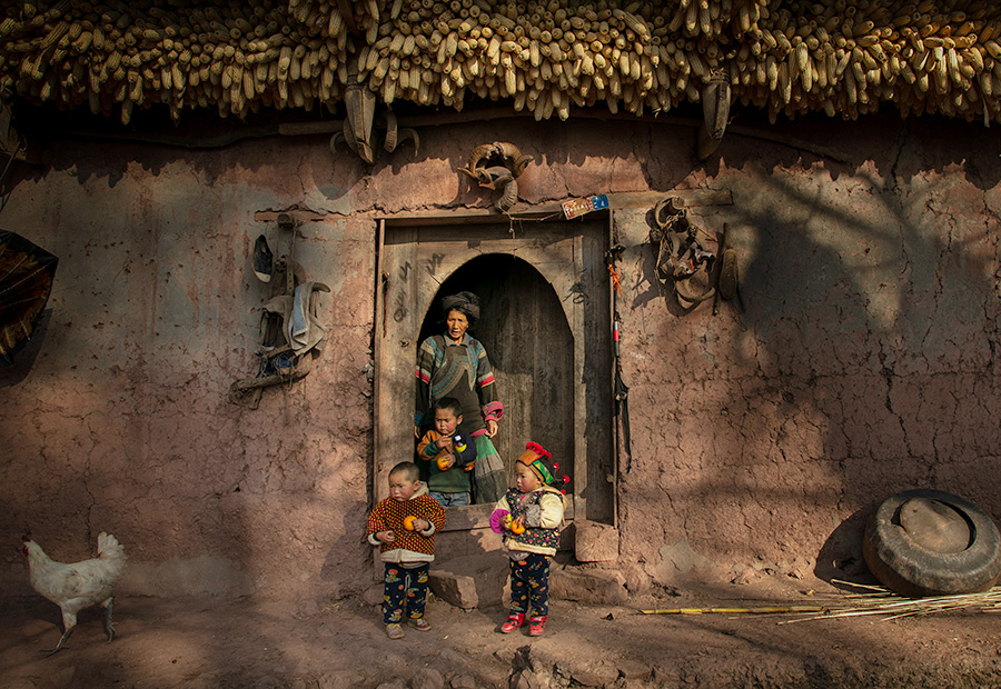 2017年12月9日,四川省凉山州美姑县的一户彝族人家门前,老人在带着