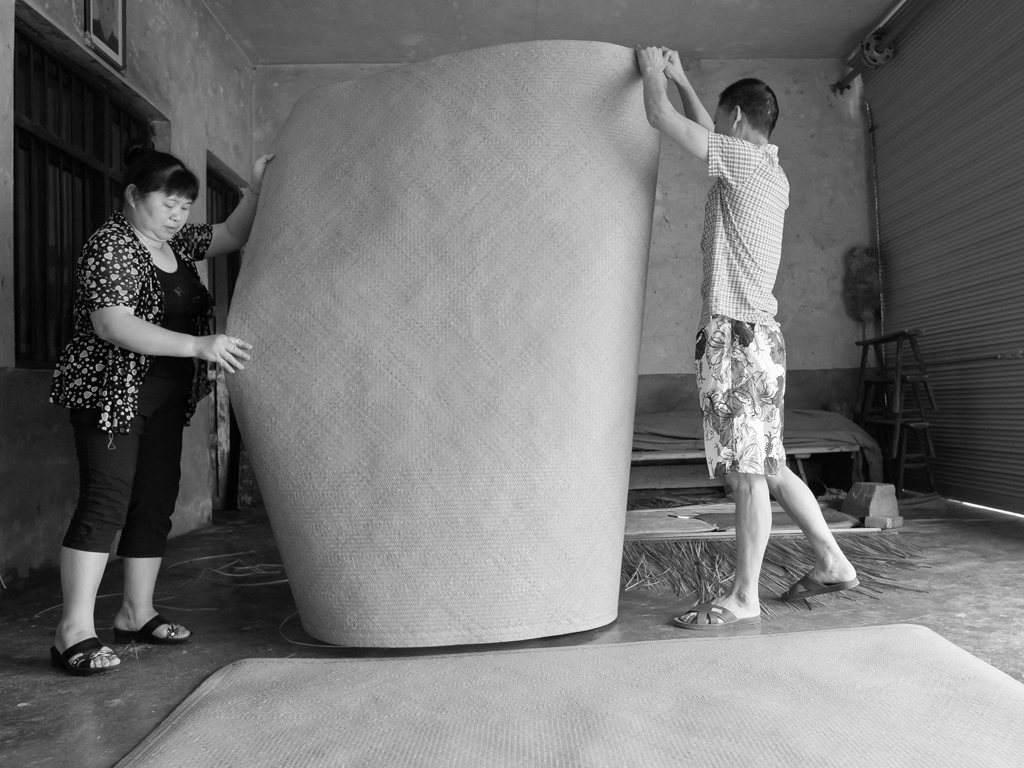 10,《夫妻共同编织幸福》组图十 席子成品(夫妻俩将打好的席子卷好