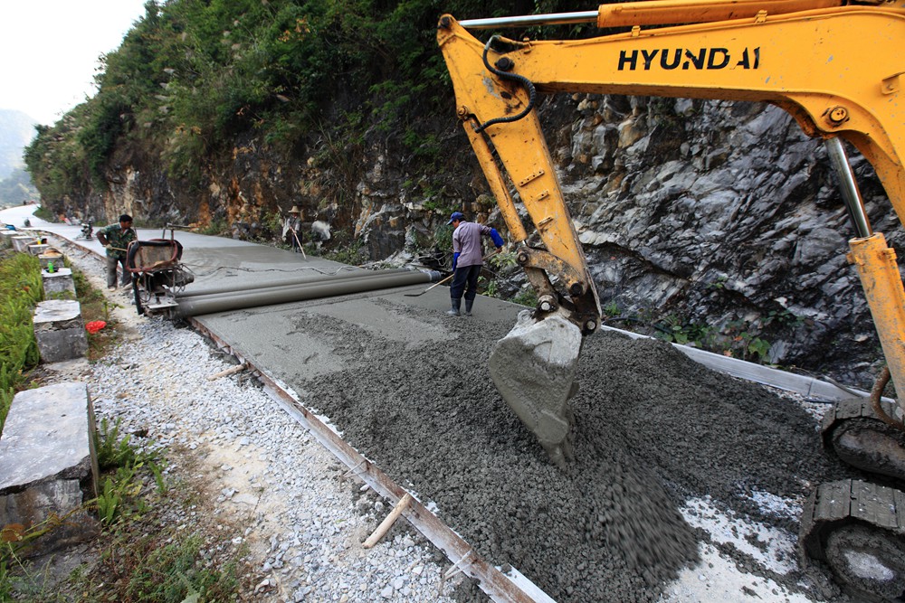 08:在广西河池市凤山县一条村级公路建设工地,工人们在铺水泥路面.