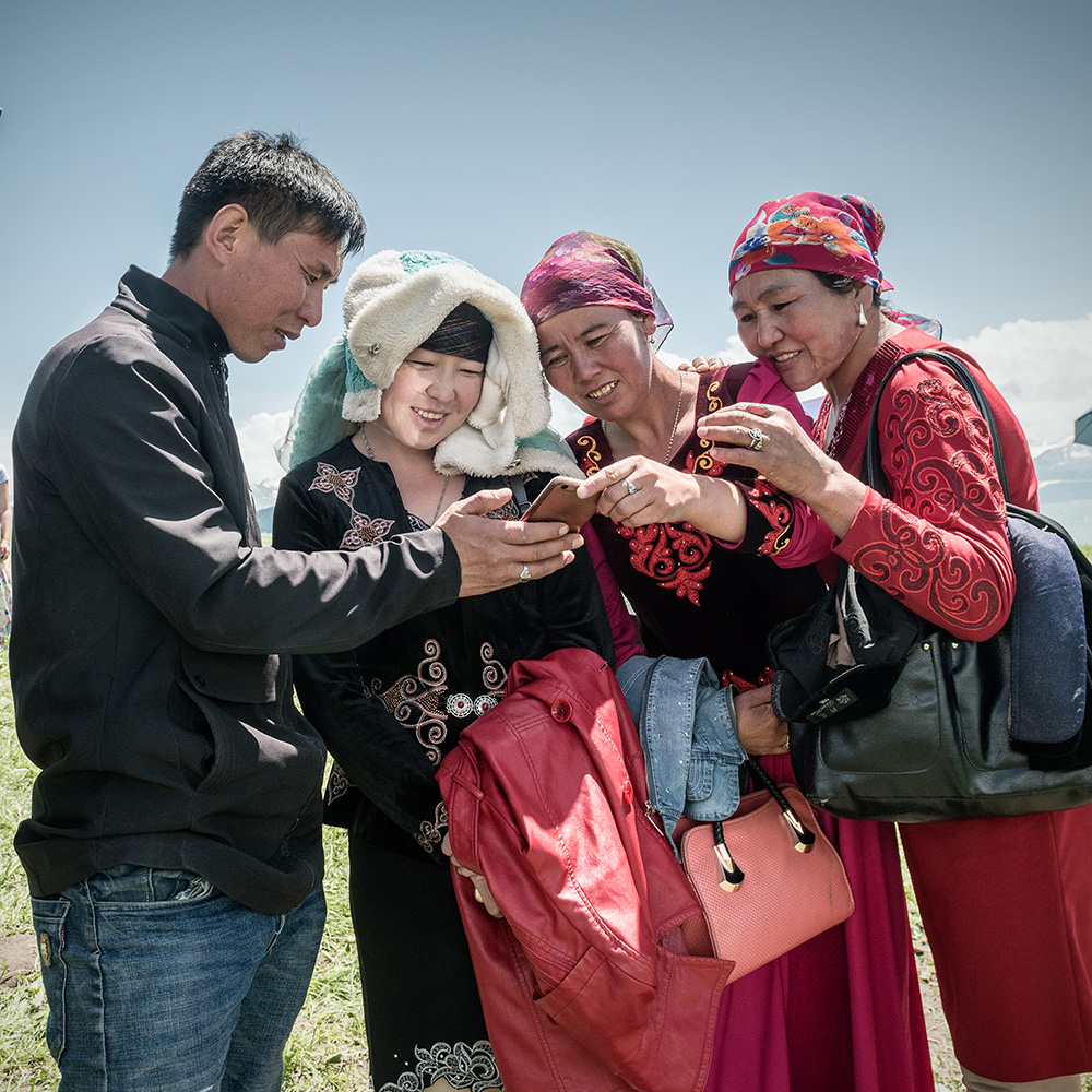 几个哈撒克族人在一块欣赏手机拍的合影照片.