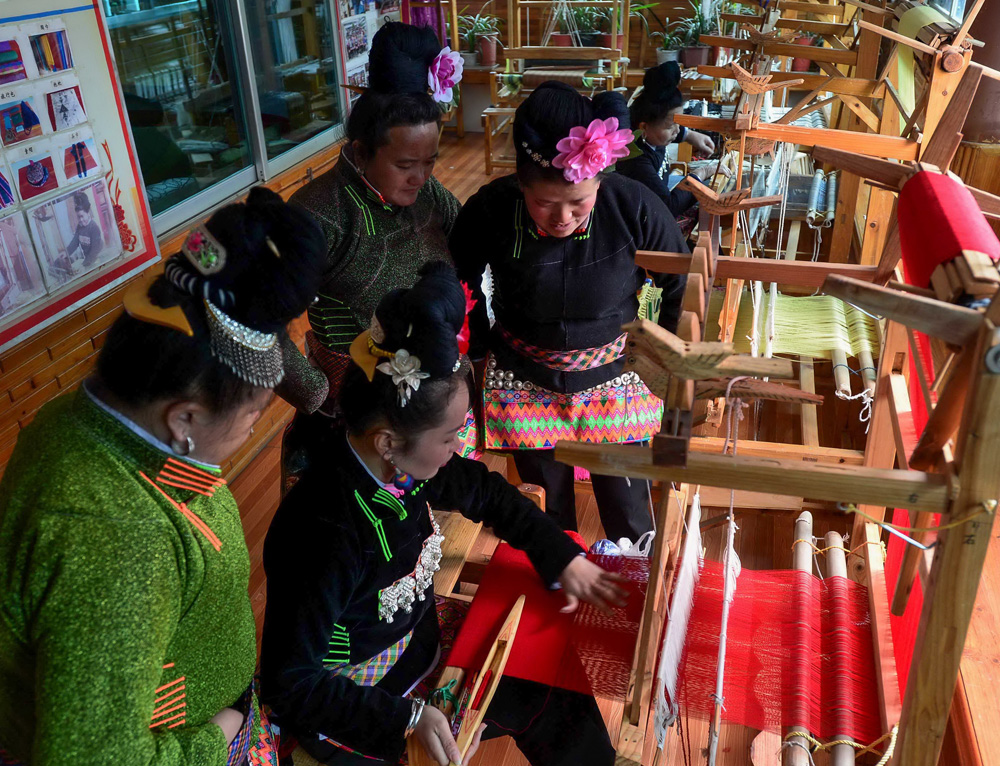 民族民间刺绣技艺传承人(坐者)在为苗族妇女培训苗族织锦技艺.