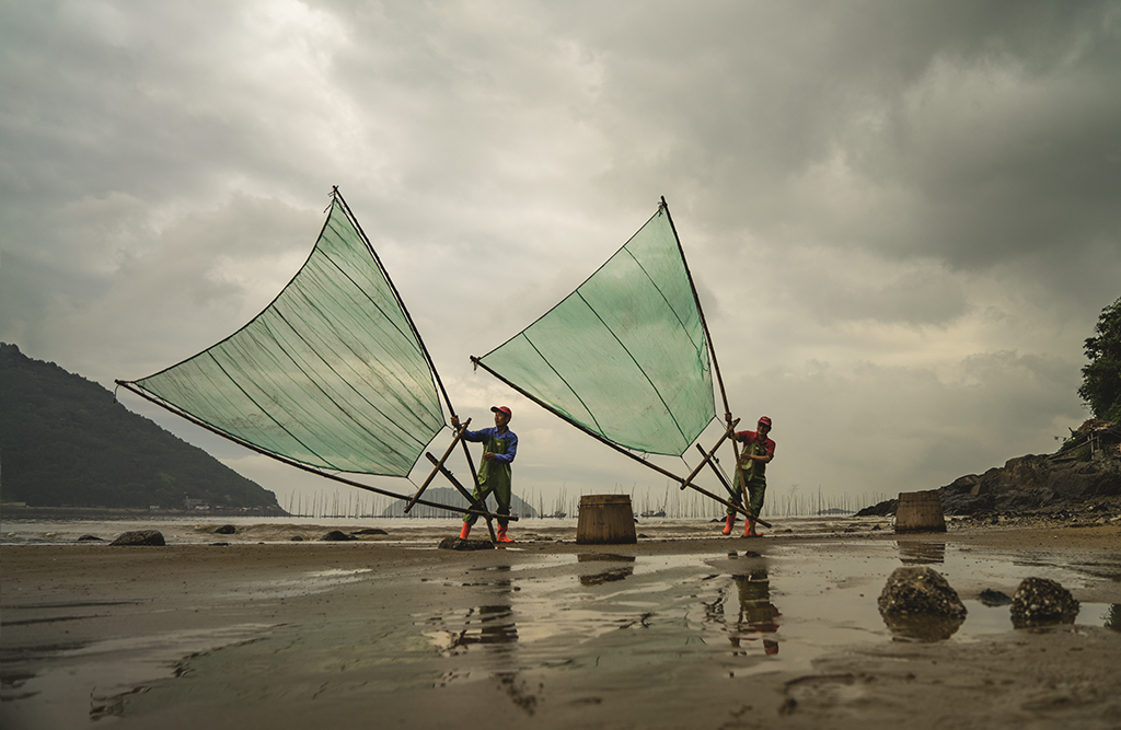 图片为渔民正在捕鱼作业,其肢体语言颇具艺感.