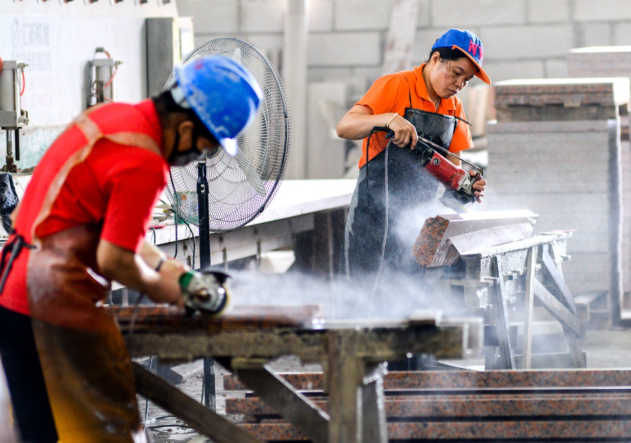 村里石材加工厂的工人忙碌生产.