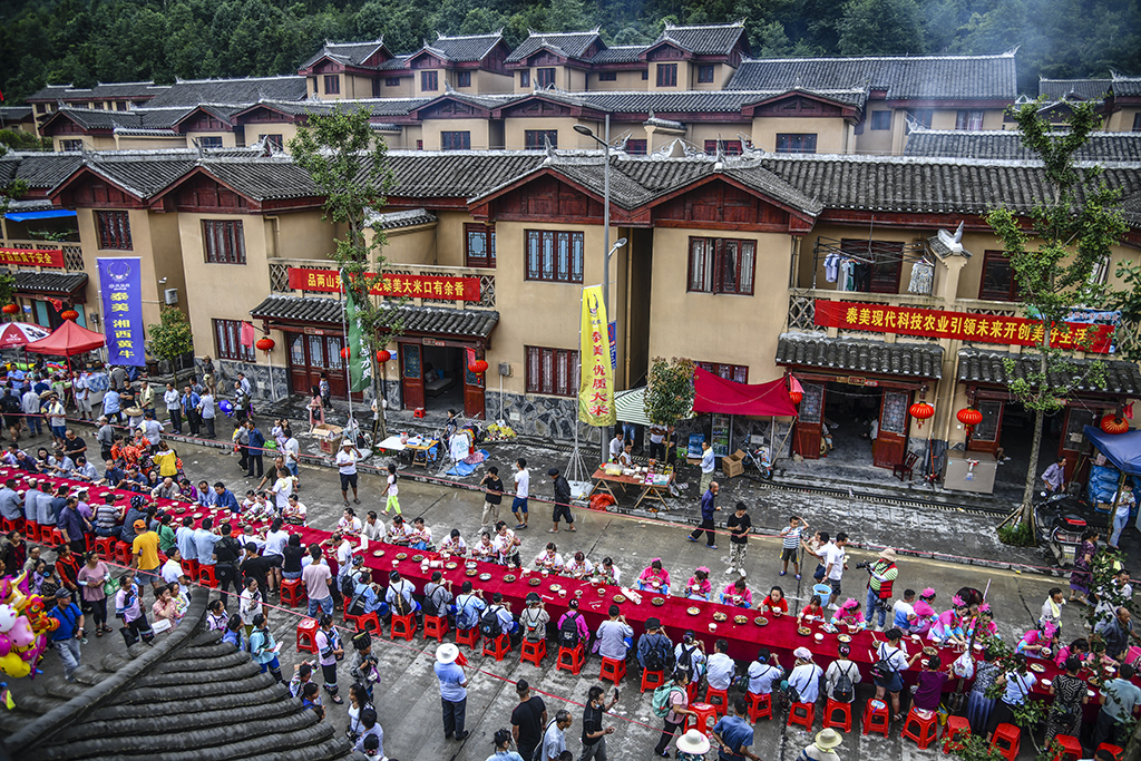 7湖南凤凰县禾库镇六月六长桌宴,背景是禾库镇扶贫房